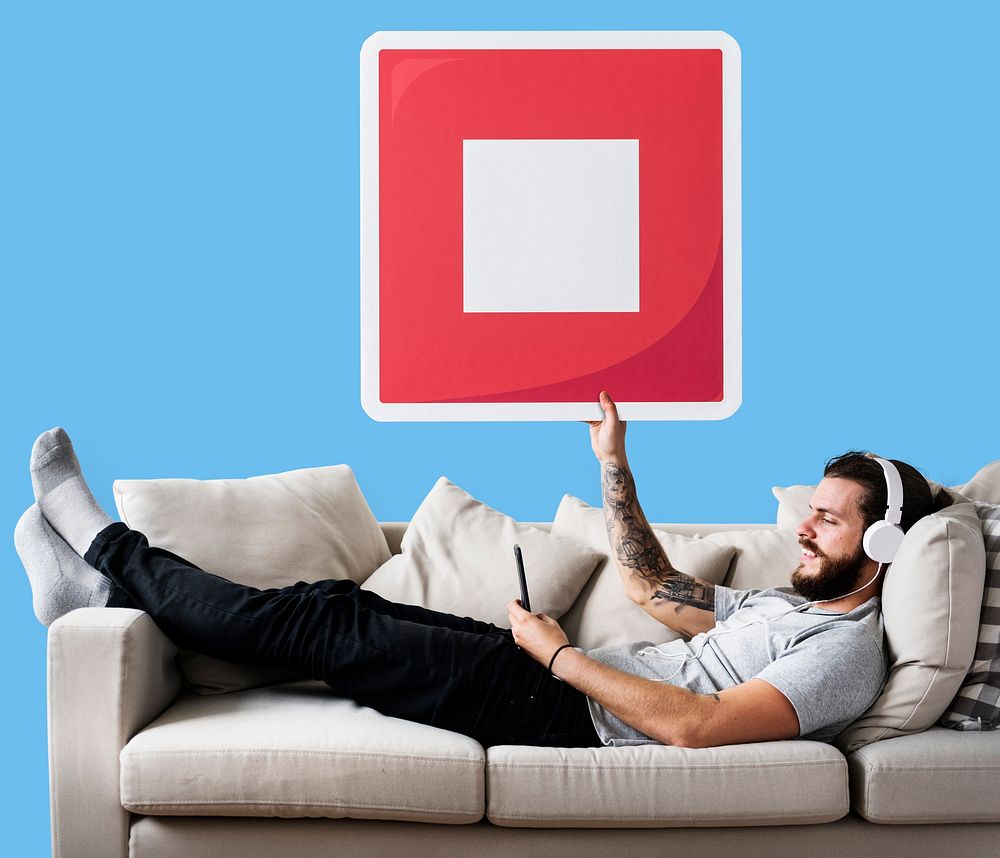 Male on a couch holding a stop button icon