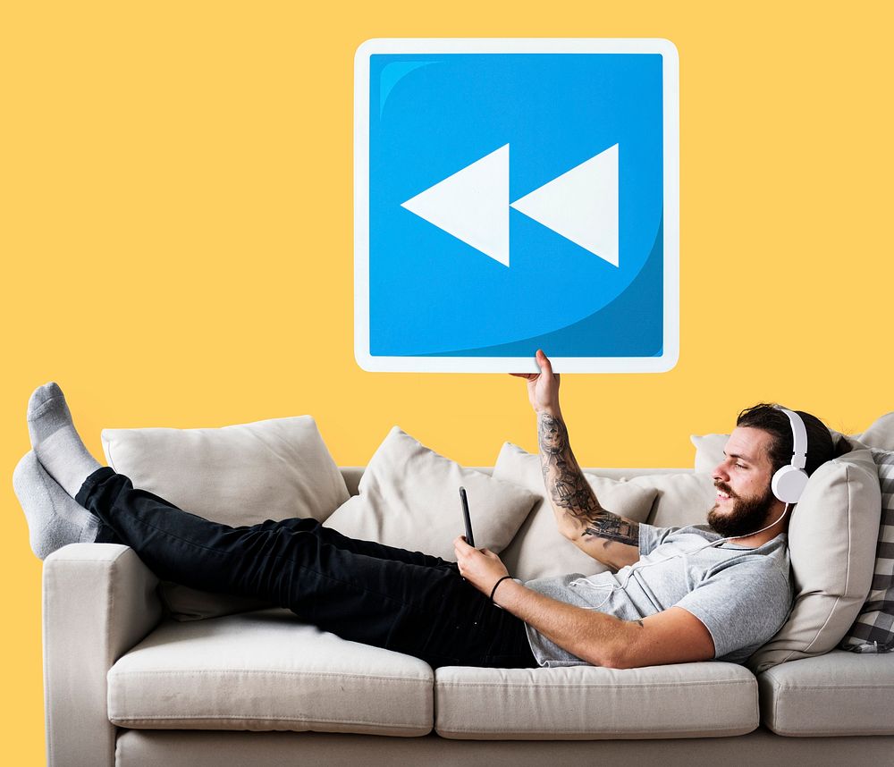 Male on a couch holding a rewind button icon