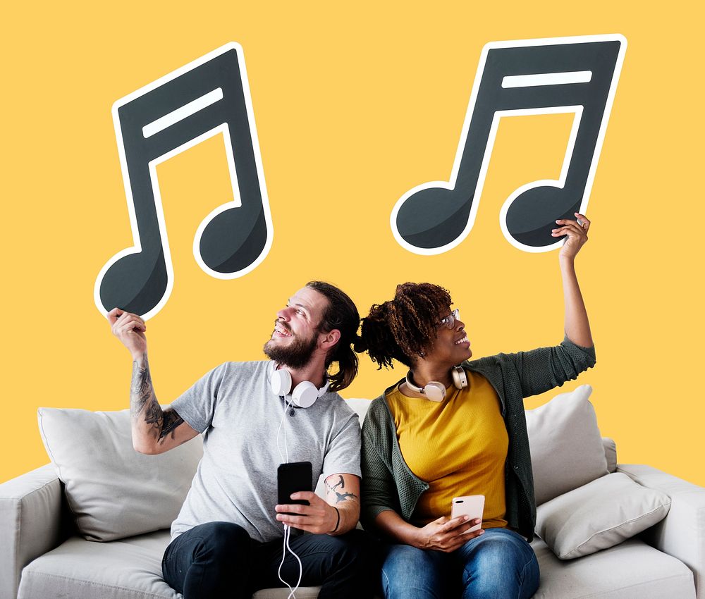Interracial couple on a couch holding  musical note icons