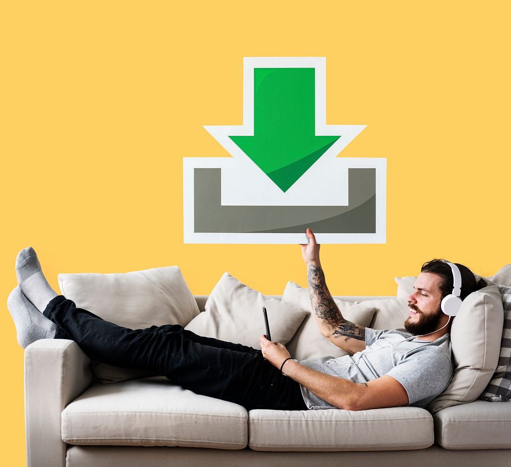 Male on a couch holding a download icon