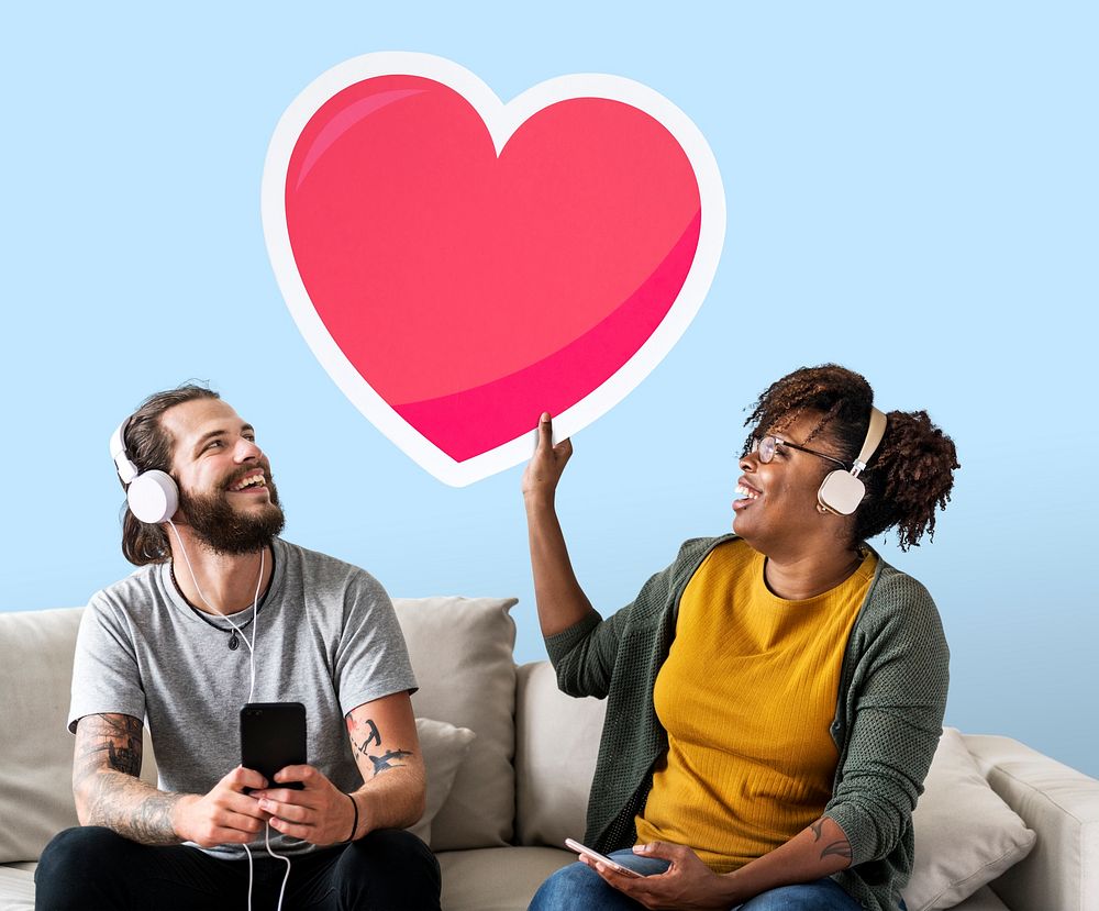 Interracial couple listening to music and holding a heart emoticon
