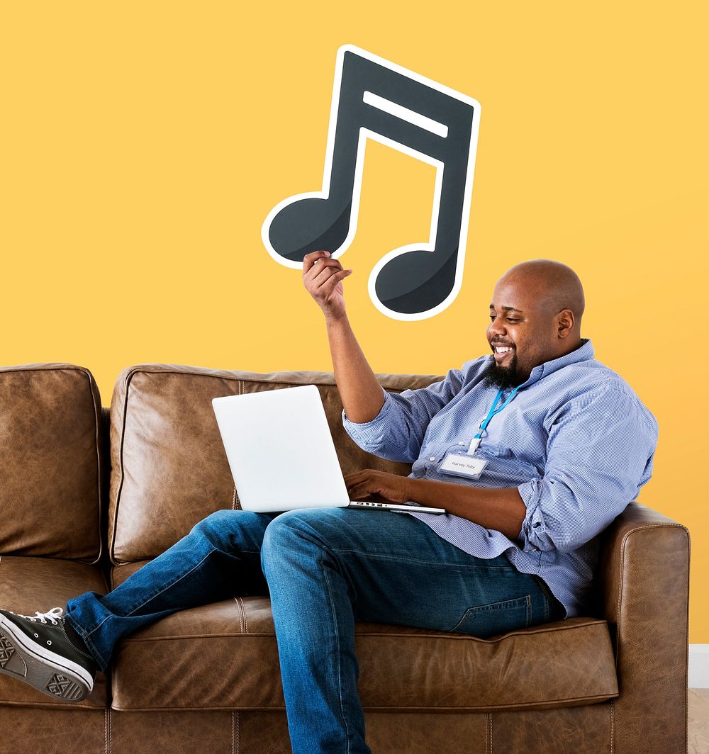 Man using a laptop and holding a musical note