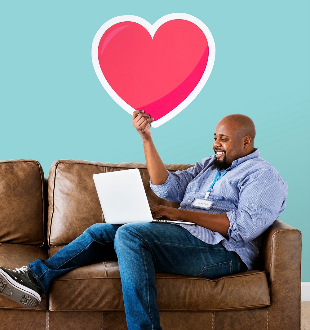 Man using a laptop and holding a heart emoticon