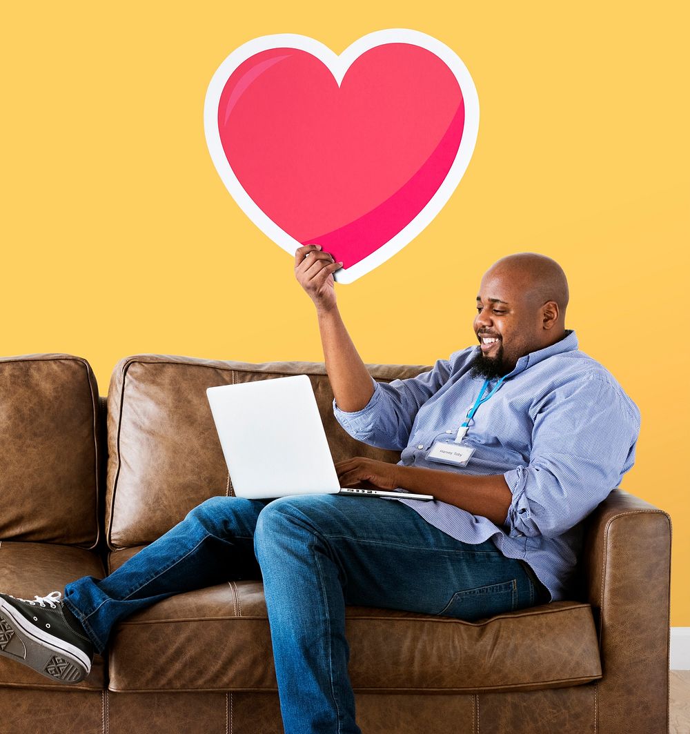 Man using a laptop and holding a heart emoticon
