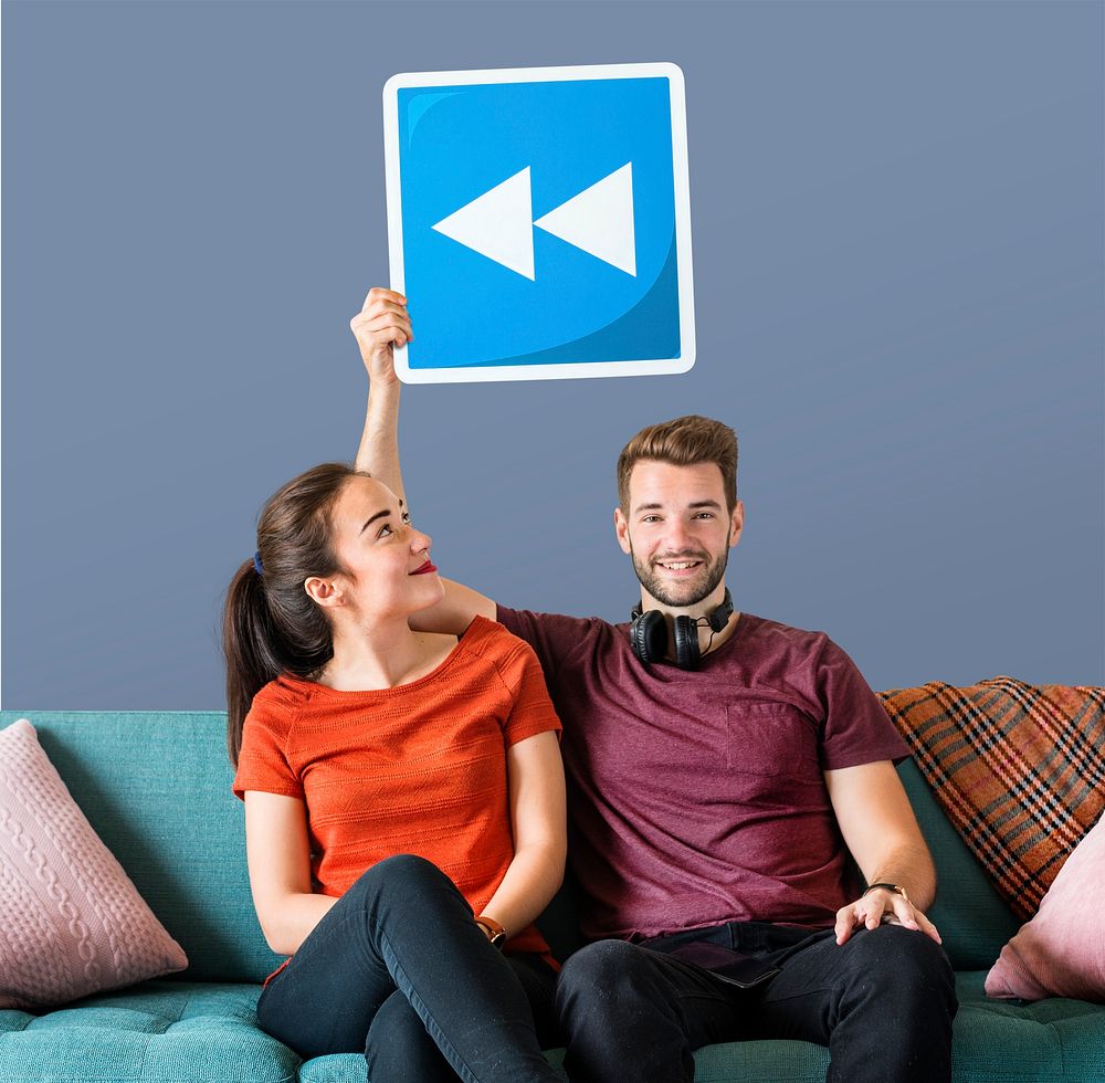 Young couple holding a rewind button icon