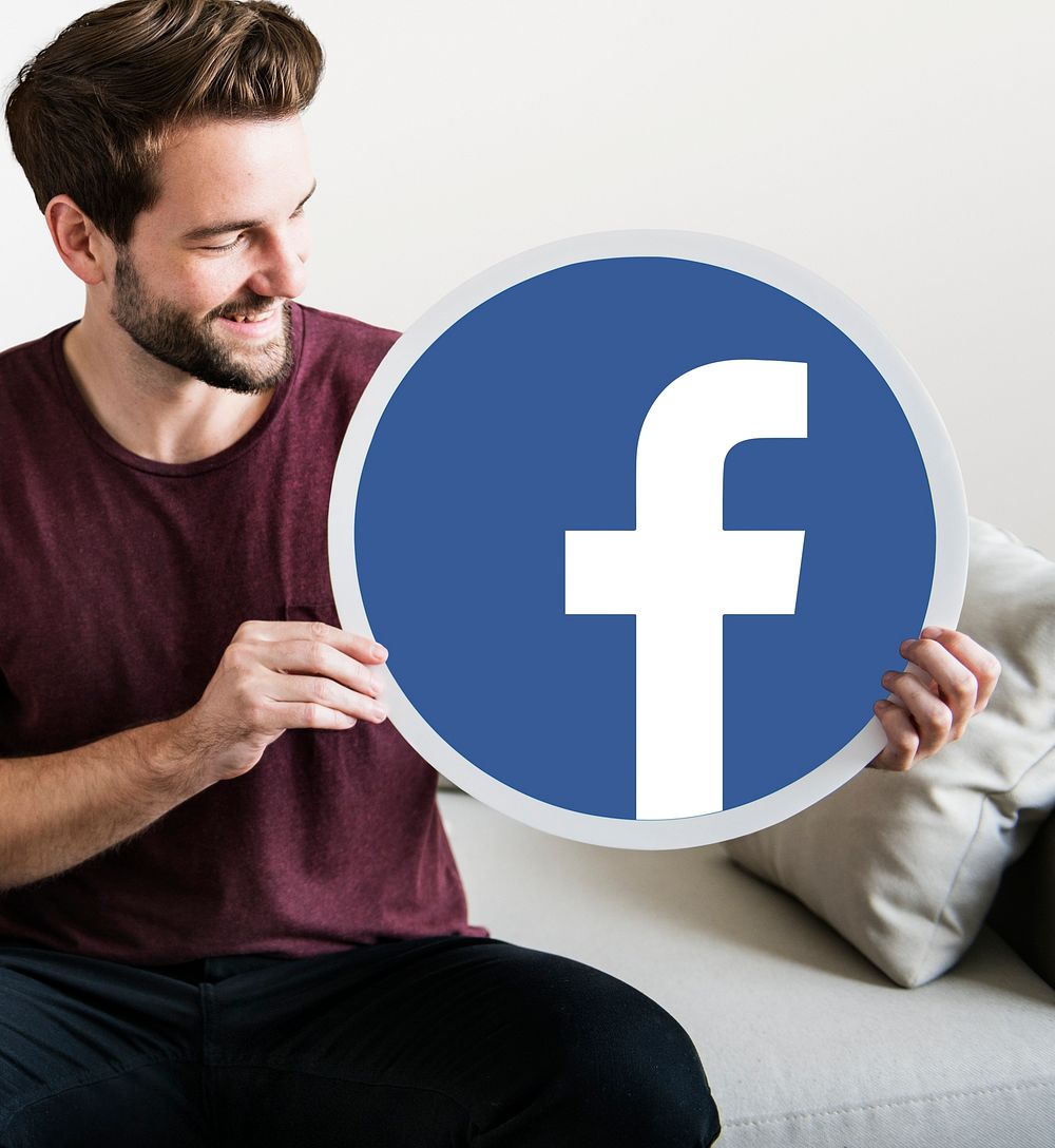 Cheerful man holding a Facebook icon