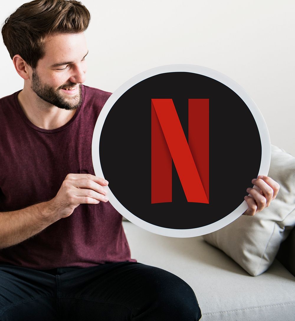 Cheerful man holding a Netflix icon