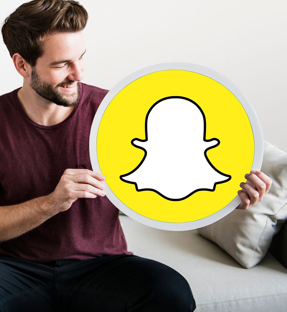 Cheerful man holding a Snapchat icon