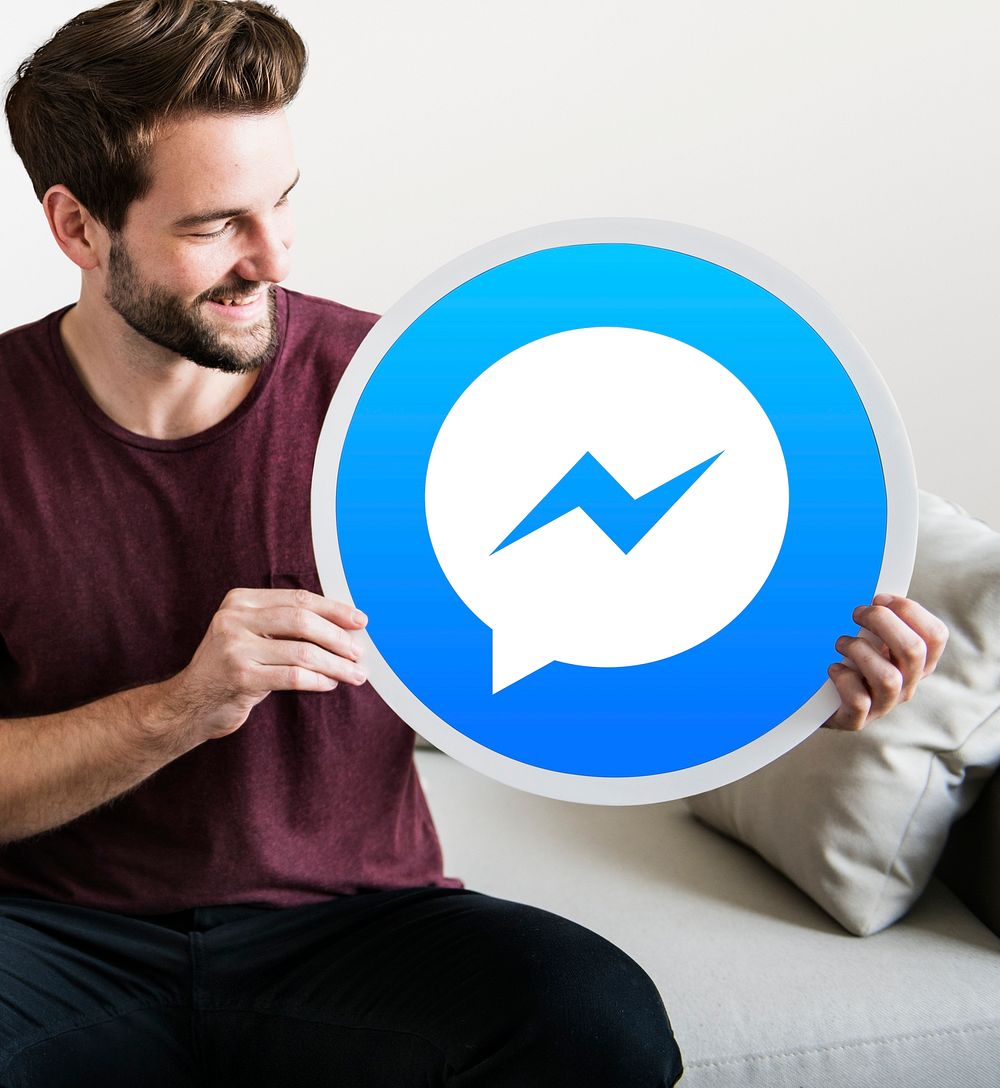 Cheerful man holding a Facebook Messenger icon