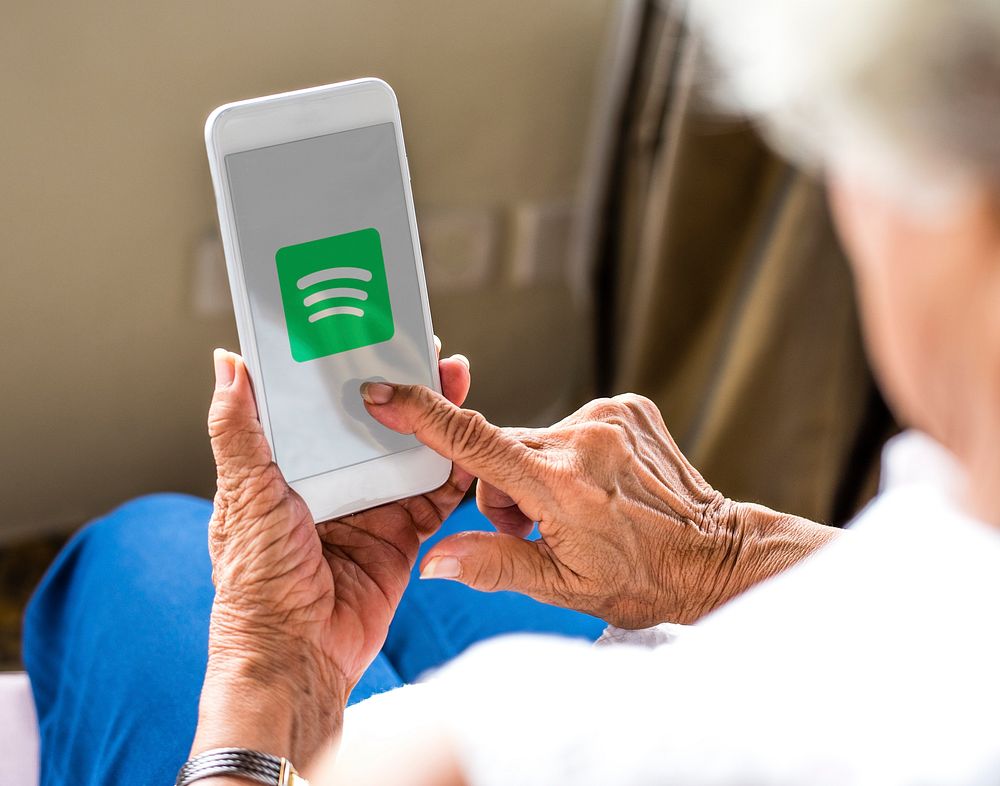 Elderly woman using Spotify application on a phone. BANGKOK, THAILAND, 1 NOV 2018.