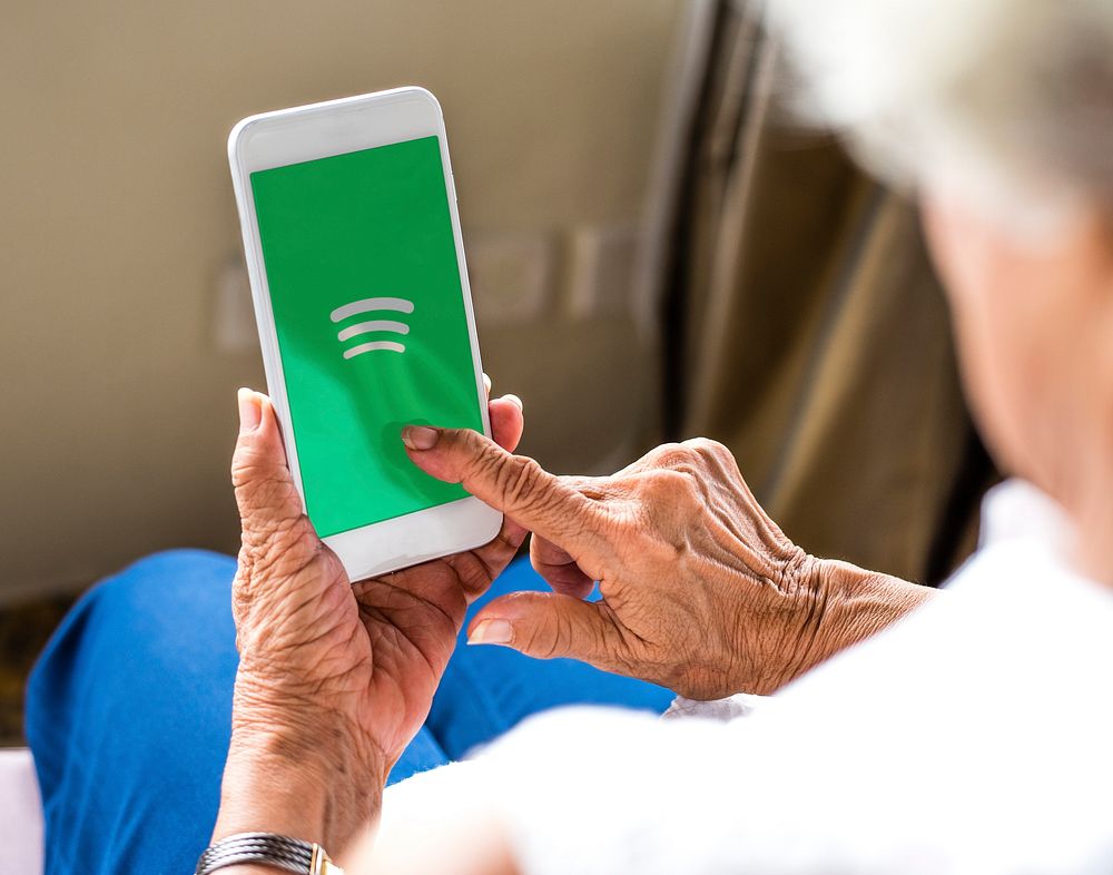 Elderly woman using Spotify application on a phone. BANGKOK, THAILAND, 1 NOV 2018.