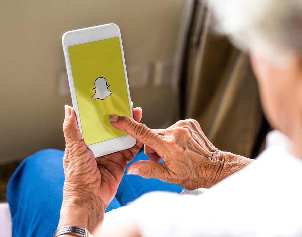 Elderly woman using Snapchat application on a phone. BANGKOK, THAILAND, 1 NOV 2018.