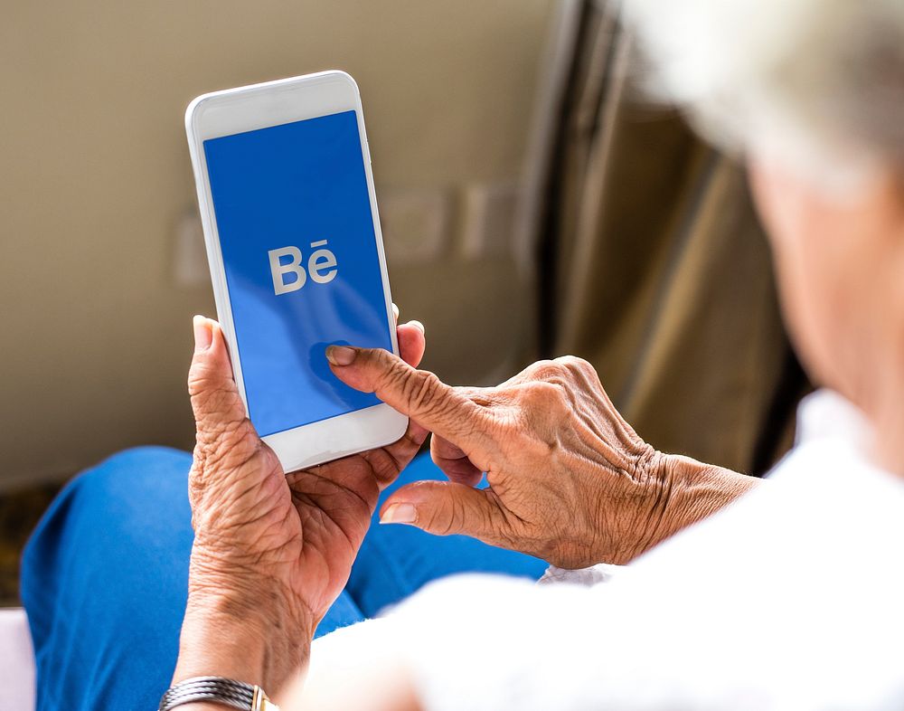 Elderly woman using Behance application on a mobile phone. BANGKOK, THAILAND, 1 NOV 2018.