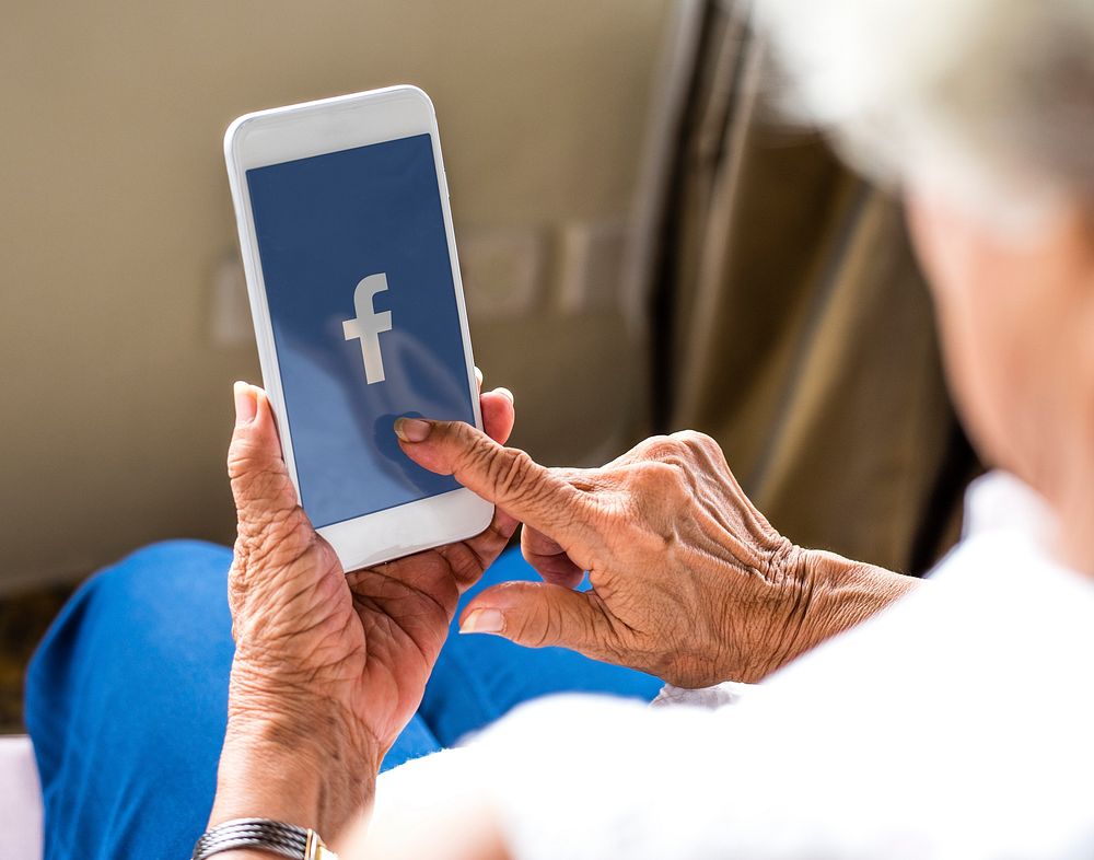 Elderly woman using Facebook application on a phone. BANGKOK, THAILAND, 1 NOV 2018.