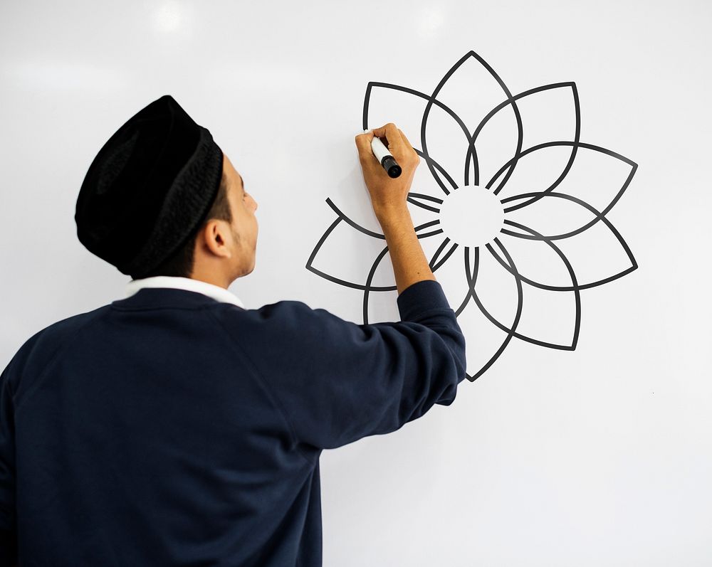 Young Muslim man drawing a mandala on a whiteboard