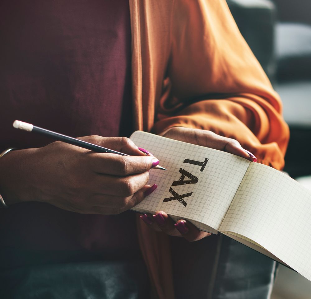 Woman writing Tax on a notepad