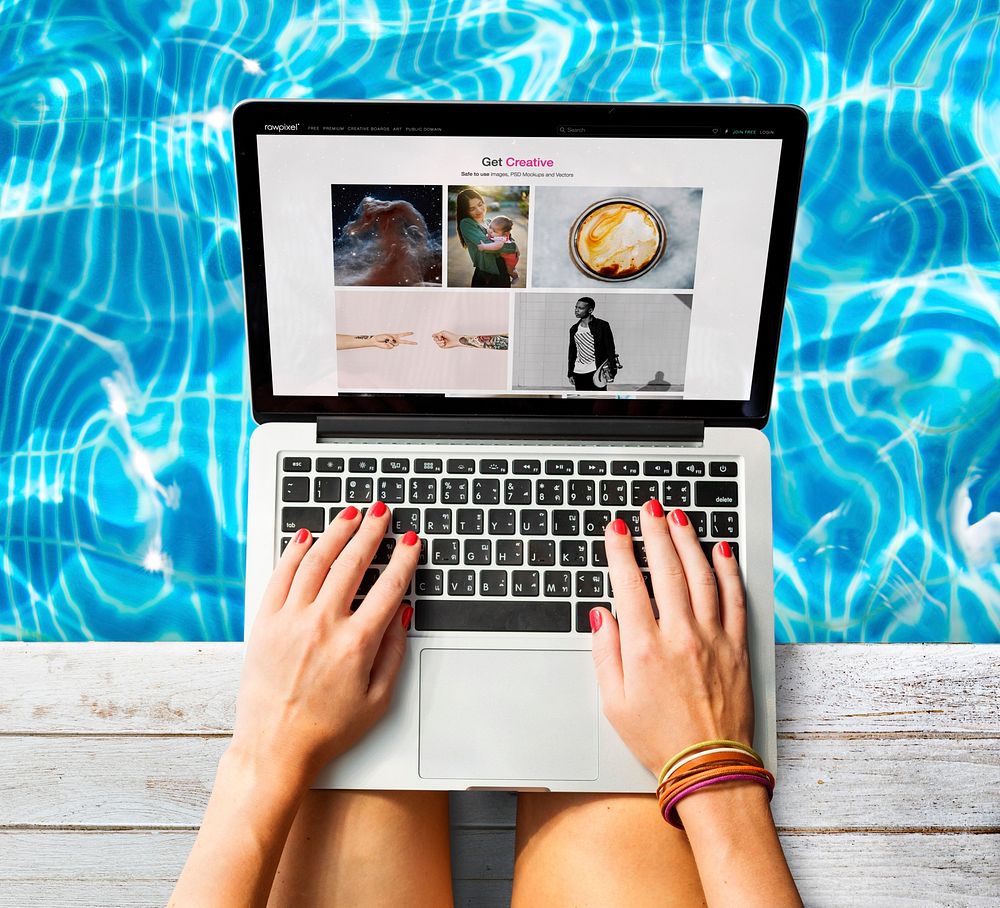 Woman using a laptop by the pool