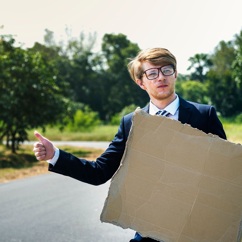 Businessman hitchhiking with a paper sign