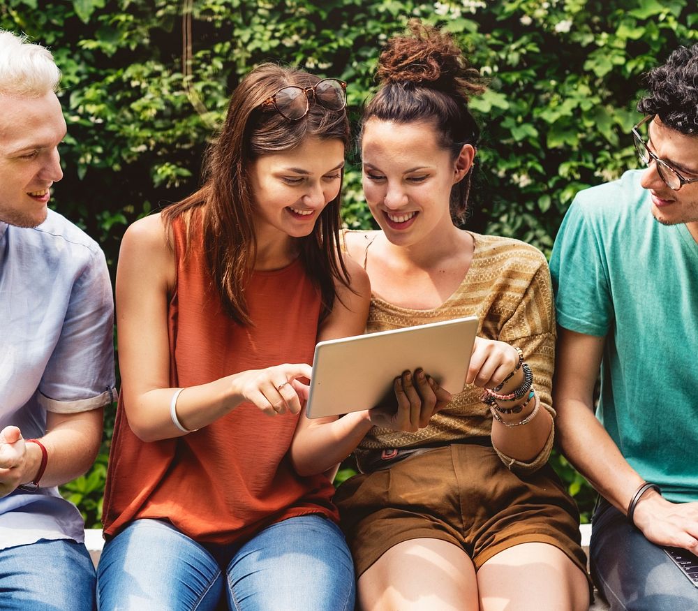 Group of diverse friends sitting using tablet together