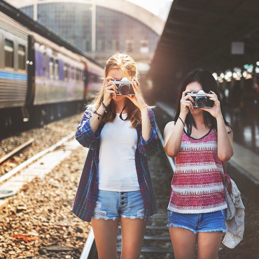 Two girls taking photos with cameras at the train station