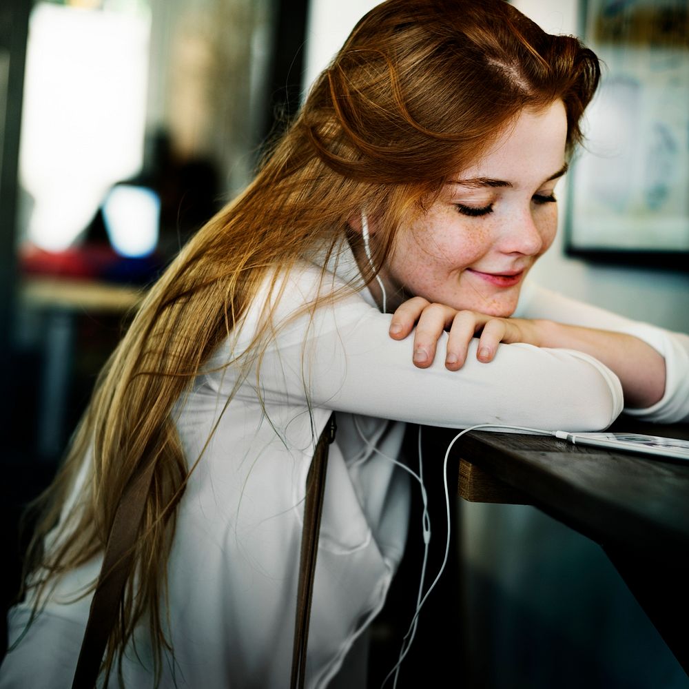 Young caucasian woman sitting listening to music