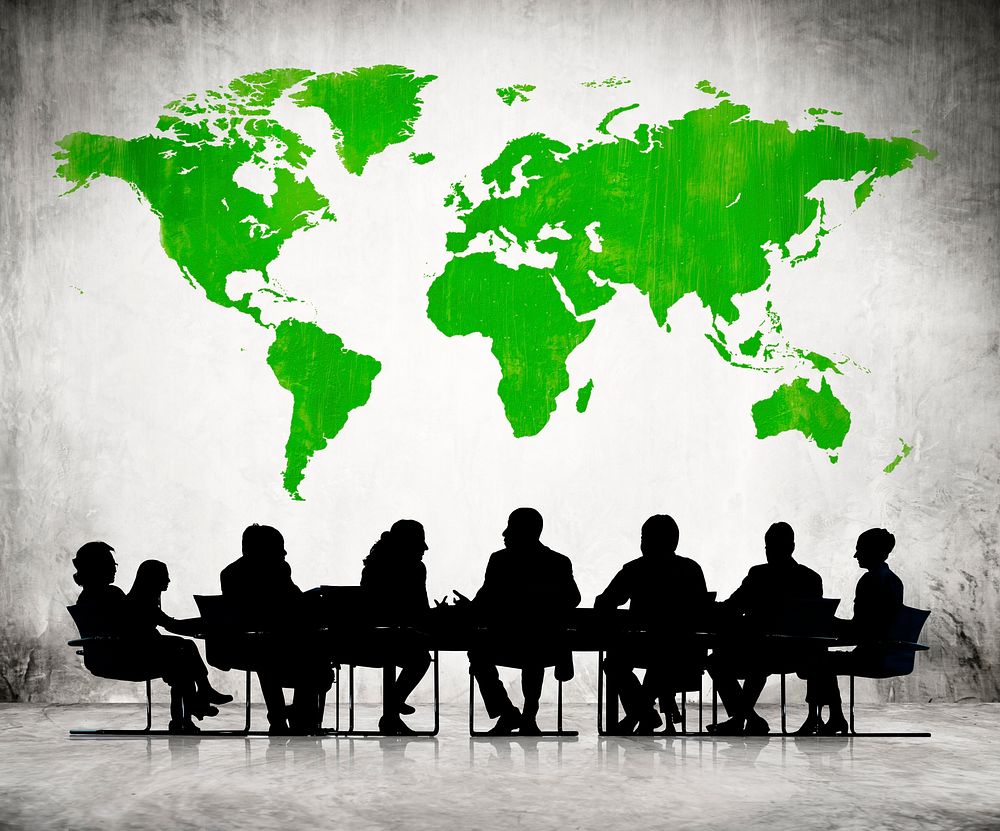 Business People Discussing Around The Conference Table And A Green Cartography Of The World Above