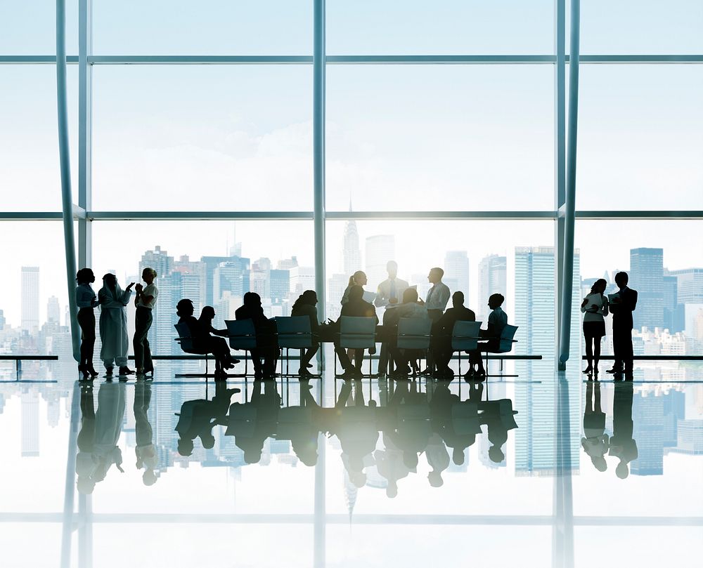 Silhouettes of business people around the conference table with a view of urban scene.