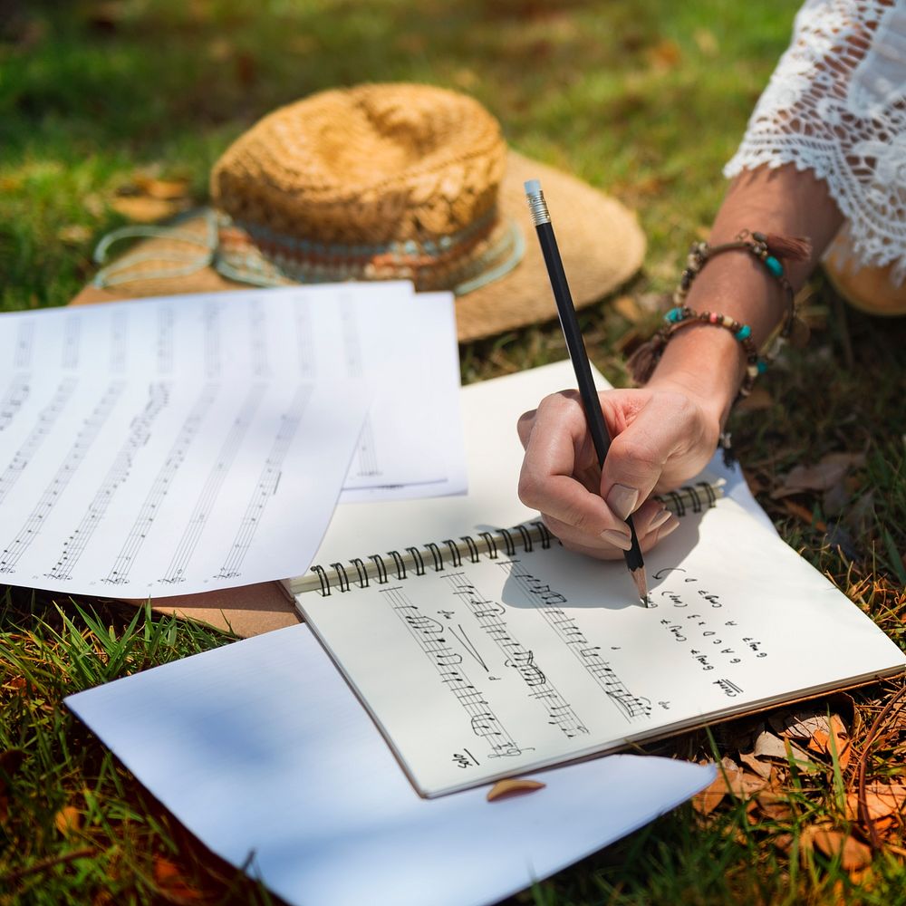 Hand writing songs on notebook outdoors
