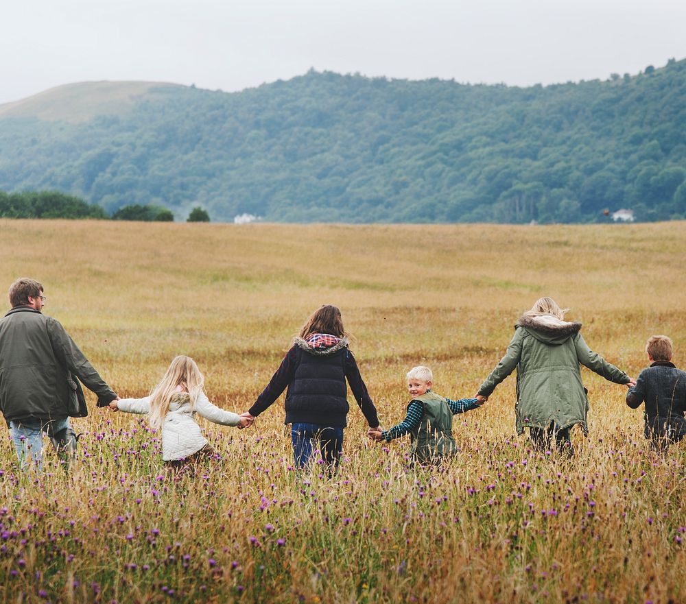 Rear view of family holding hands walking in a field