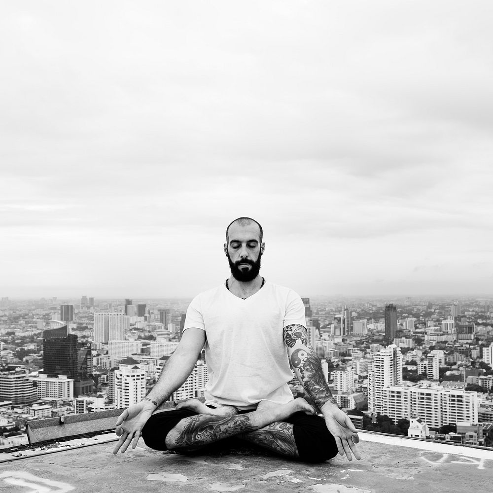 Man practicing yoga on the rooftop and cityscape background