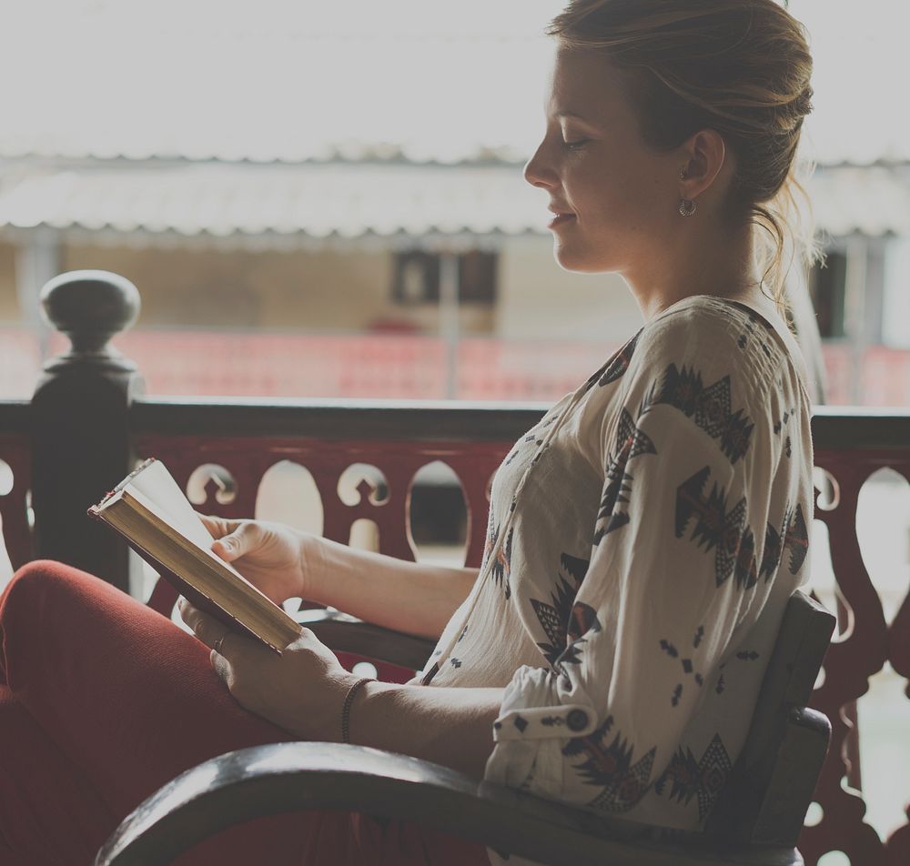 Caucasian woman reading the book at the balcony