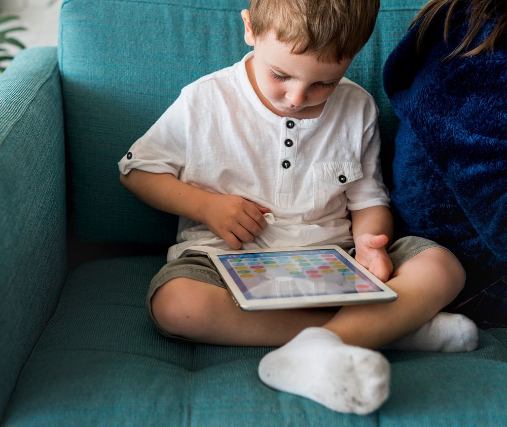 Little boy using a tablet on a couch