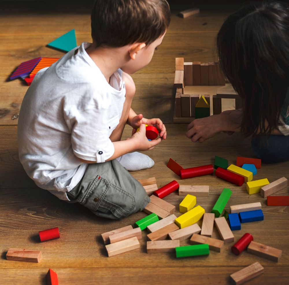 Little boy playing wooden blocks on a floor