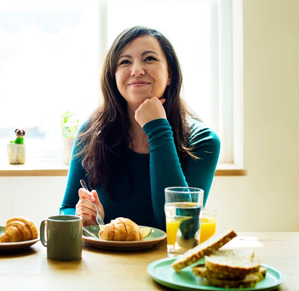 Cheerful woman eating breakfast at home