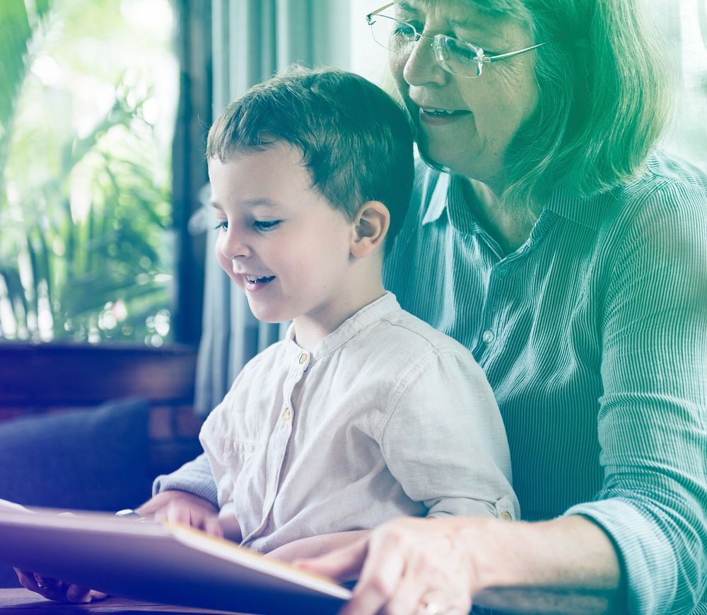 Grandmother and little cute grandson reading book together