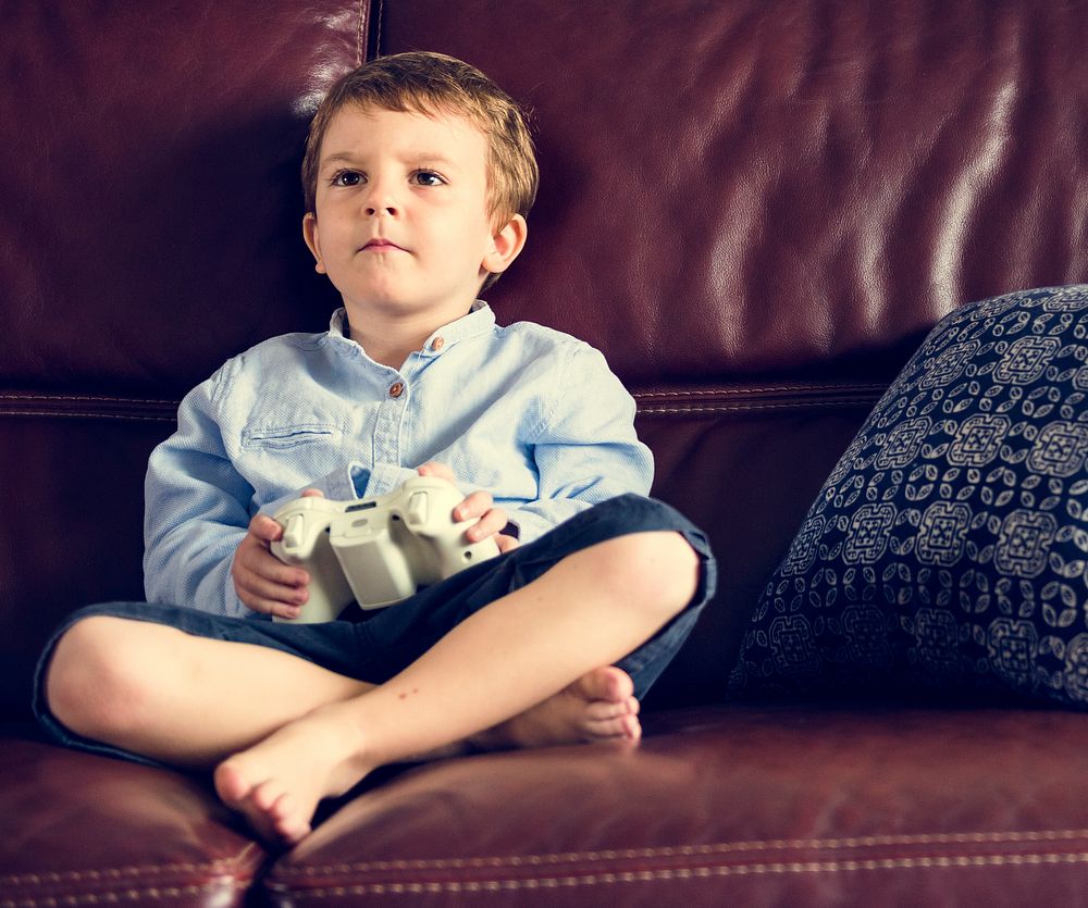 Boy Holiday Playing Game Sitting on Sofa at His Home