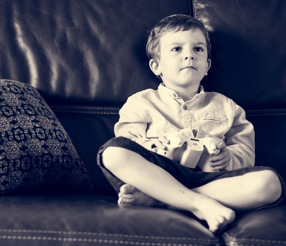 Boy Holiday Playing Game Sitting on Sofa at His Home