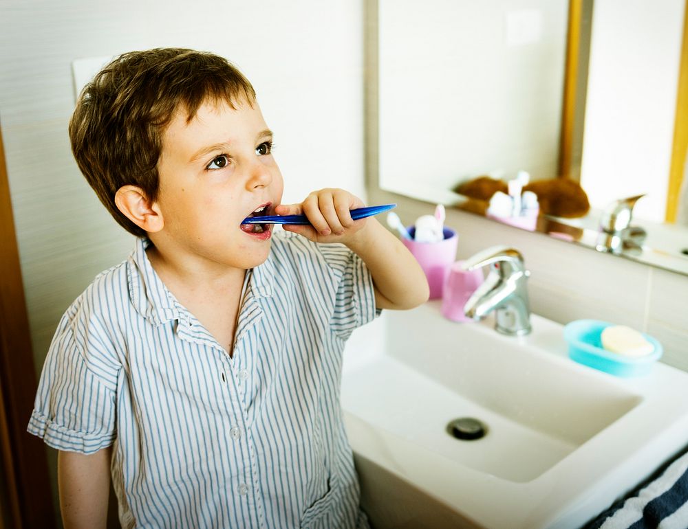 A boy is learning how brush his teeth.