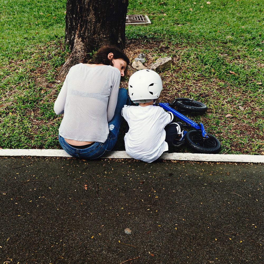 Mom teaching son how to ride a bicycle outdoors