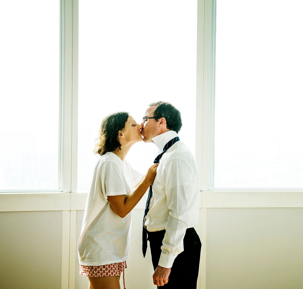 Woman kissing husband goodbye in the morning
