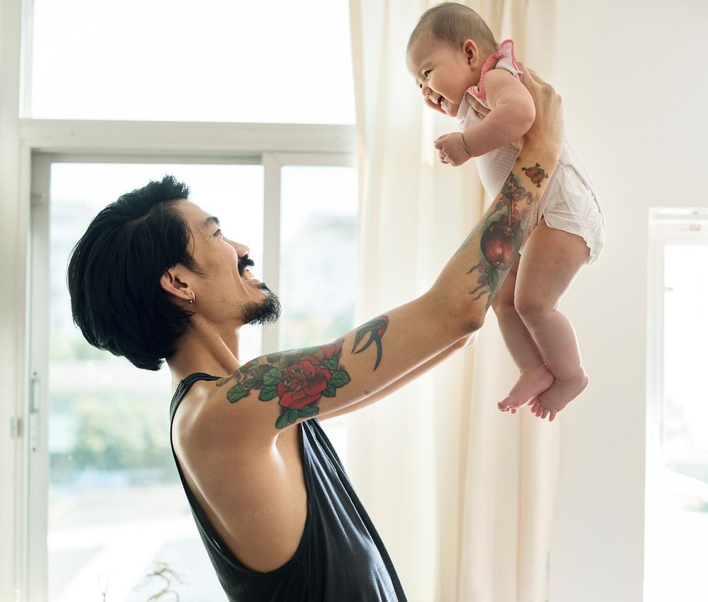 Asian dad holding his baby up with love