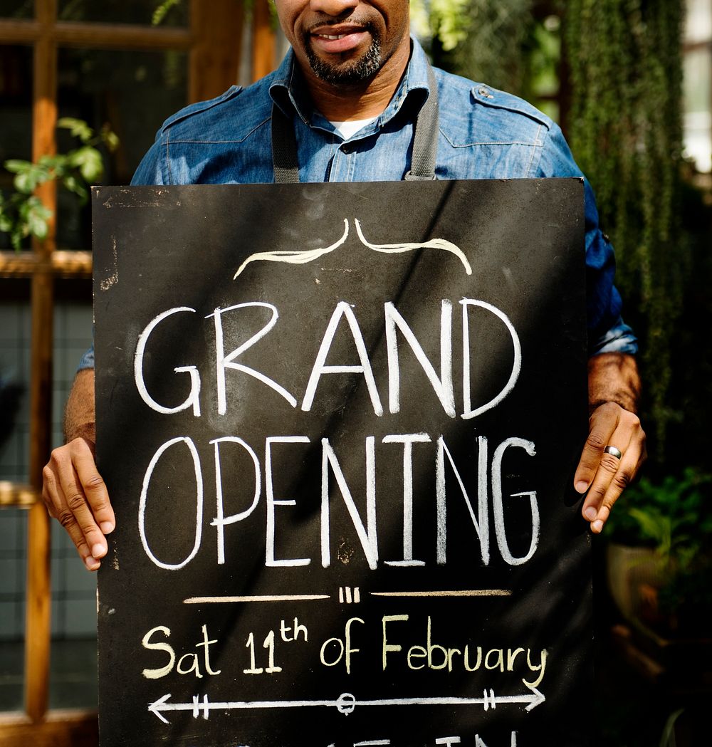 Adult Man Standing with Grand Opening Sign