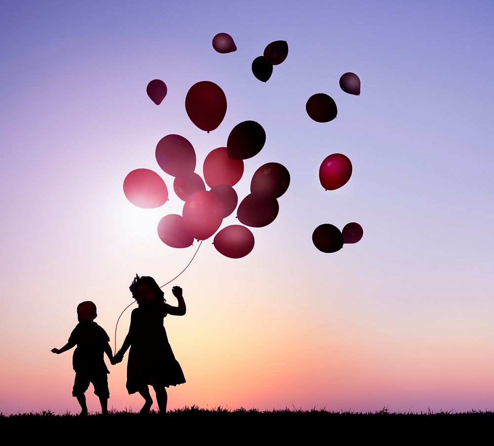 Two kids outdoor holding balloons together