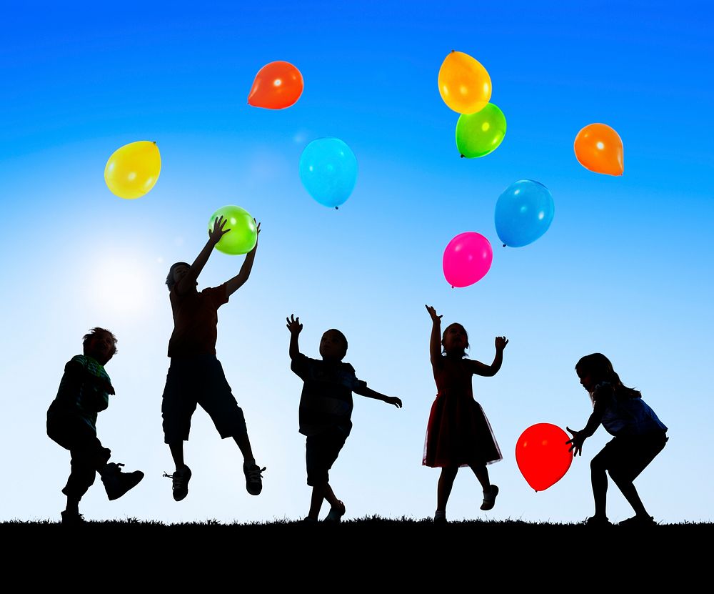 Silhouettes of Cheerful Children Playing Balloons Outdoors