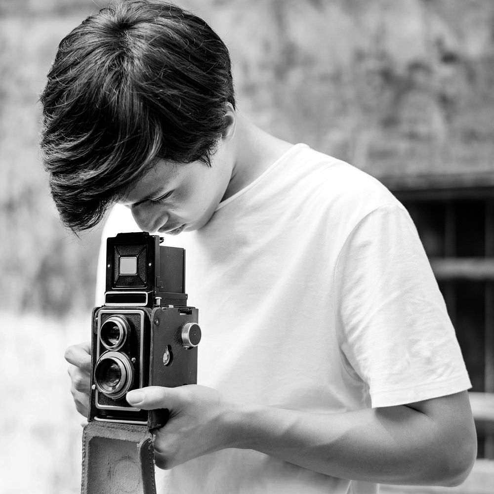 Asian guy takes photo with vintage camera