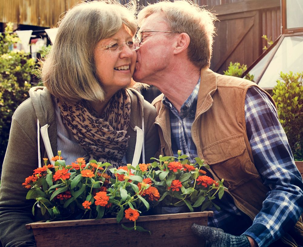 Senior Couple Man Giving Woman a Cheek Kiss and Flowers