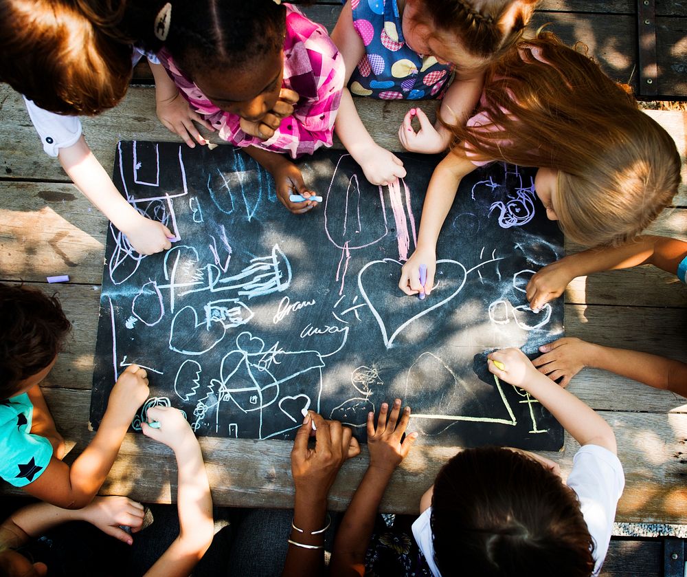 Diverse group of kids drawing on a blackboard