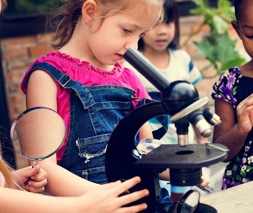 Group of children learning science by microscope