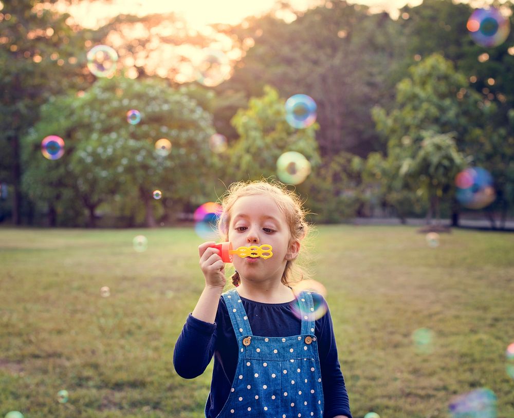 Kindergarten schoolgirl playing blowing bubbles fun