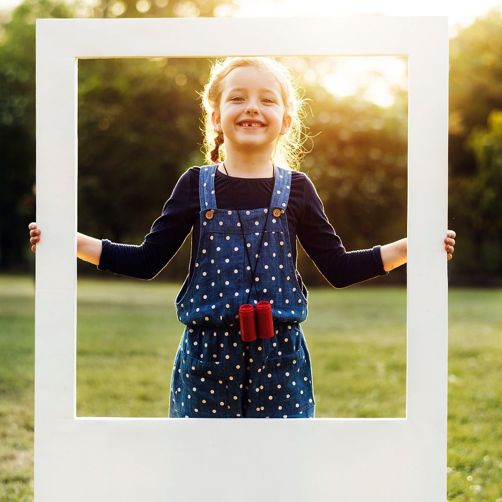 A girl is holding a frame in a park